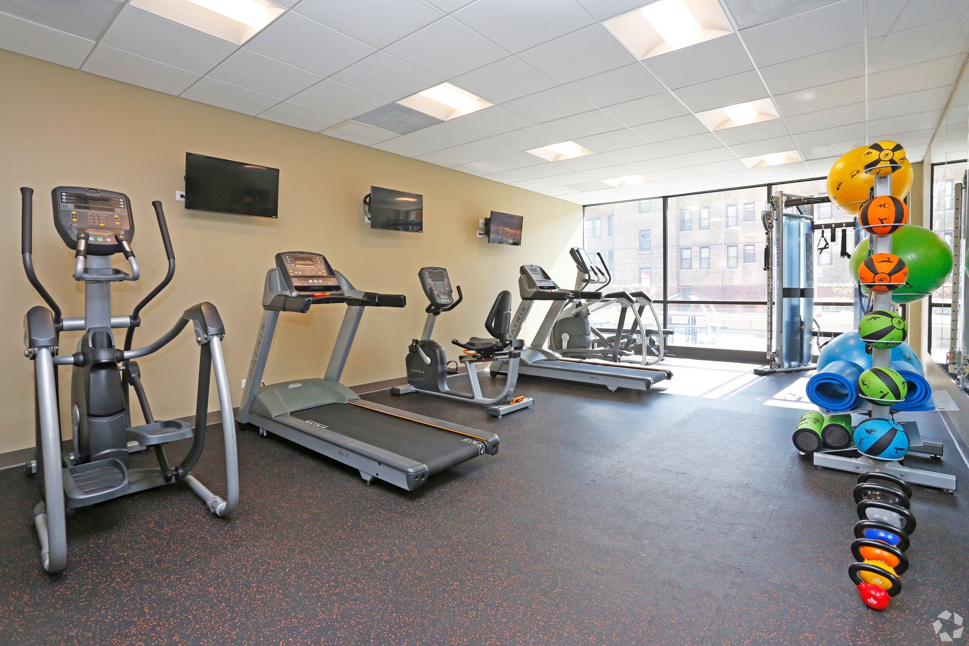 Gym with exercise equipment, including treadmills, elliptical, stationary bikes, and weights.
