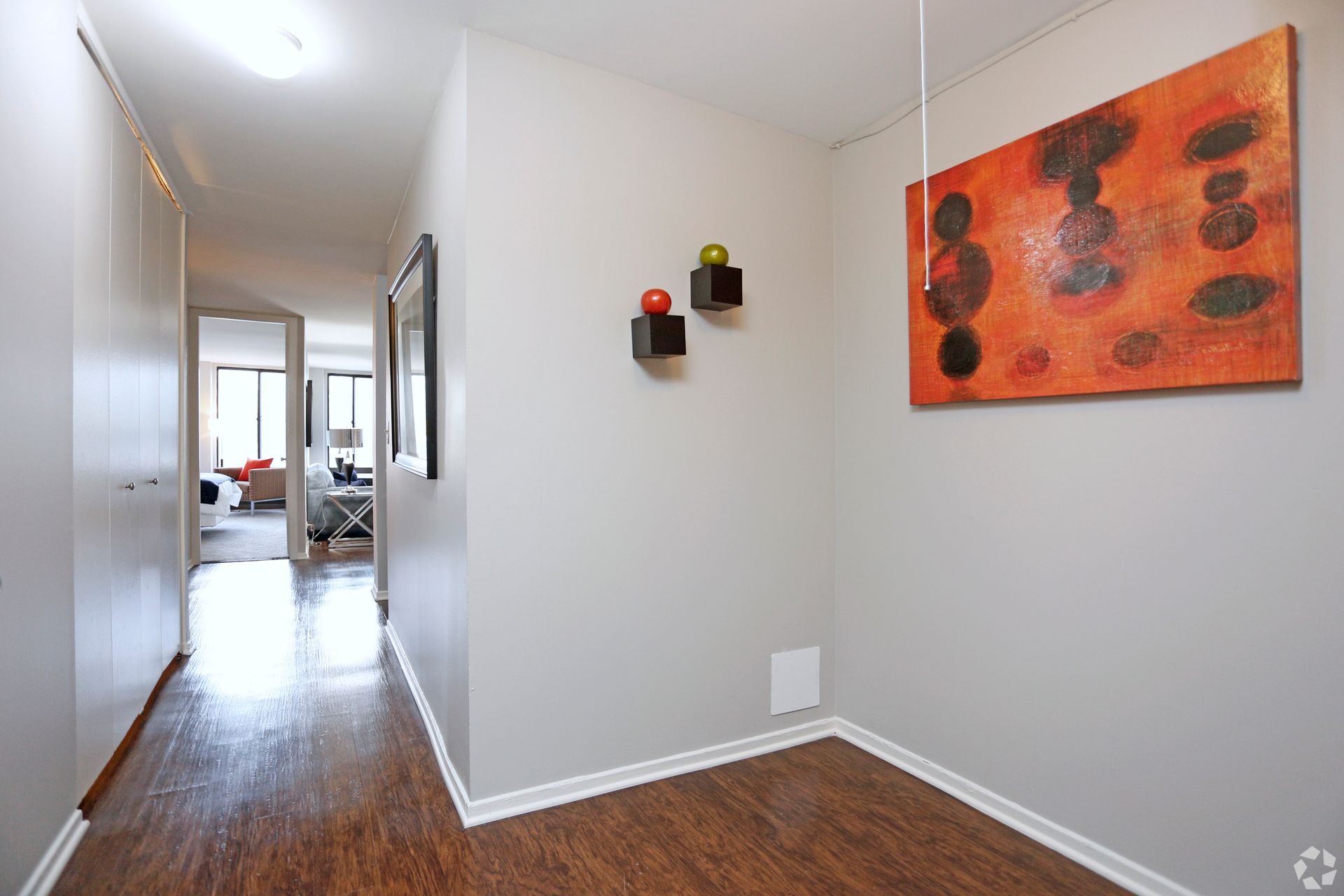 Hallway with wooden floors and gray walls. Abstract art and decorative cubes hang on the right wall.