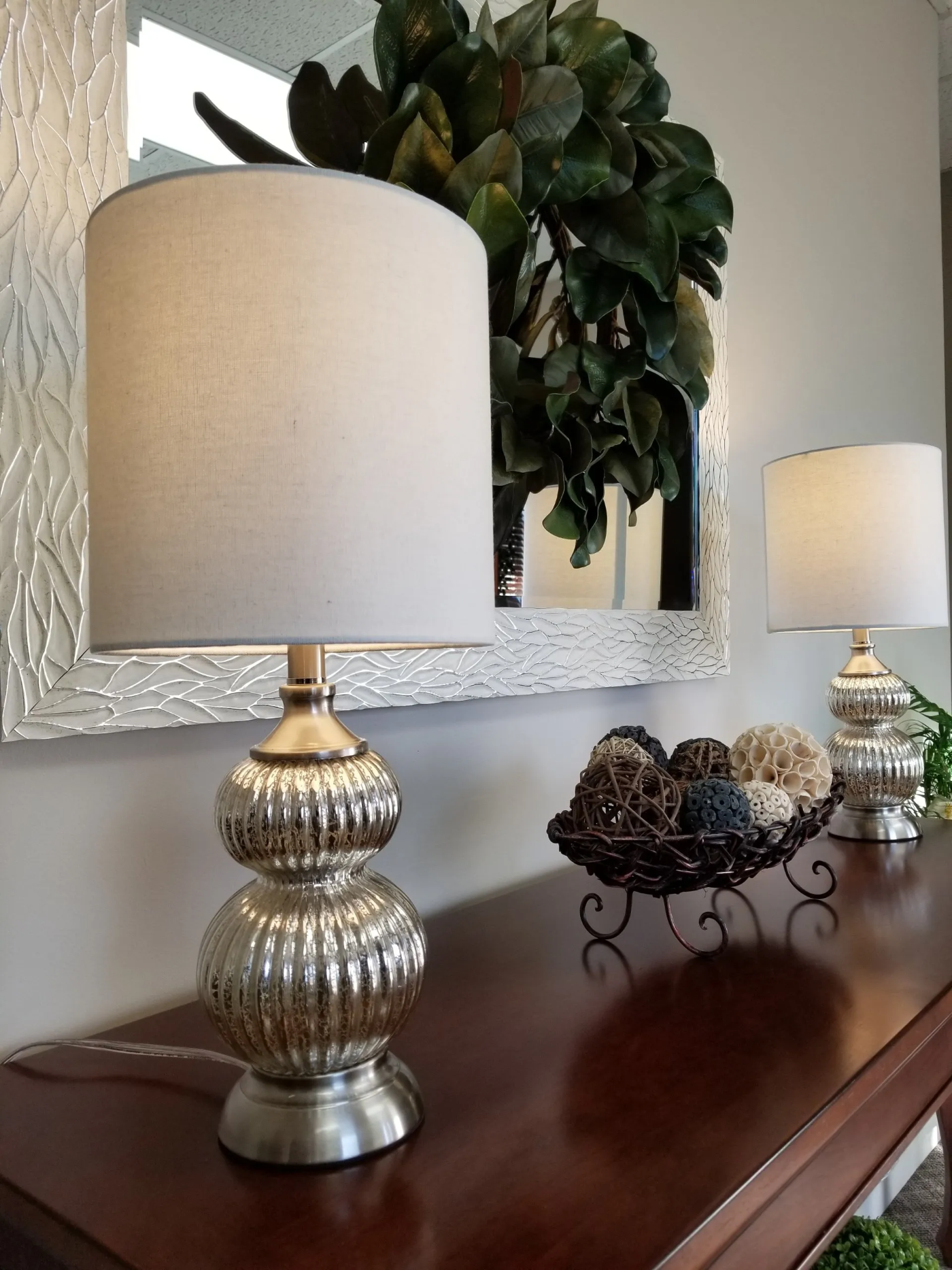 A table with two lamps and a mirror above it