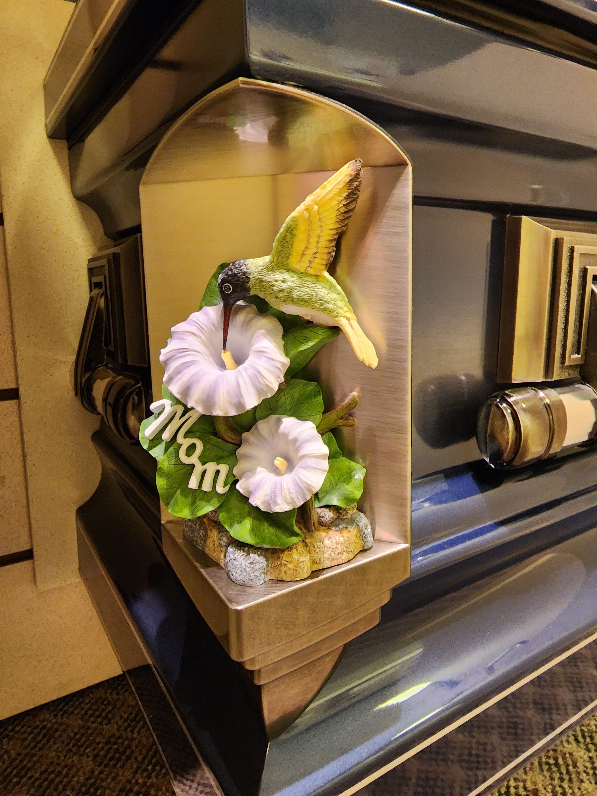 A photo of a hummingbird figurine of corner of a casket