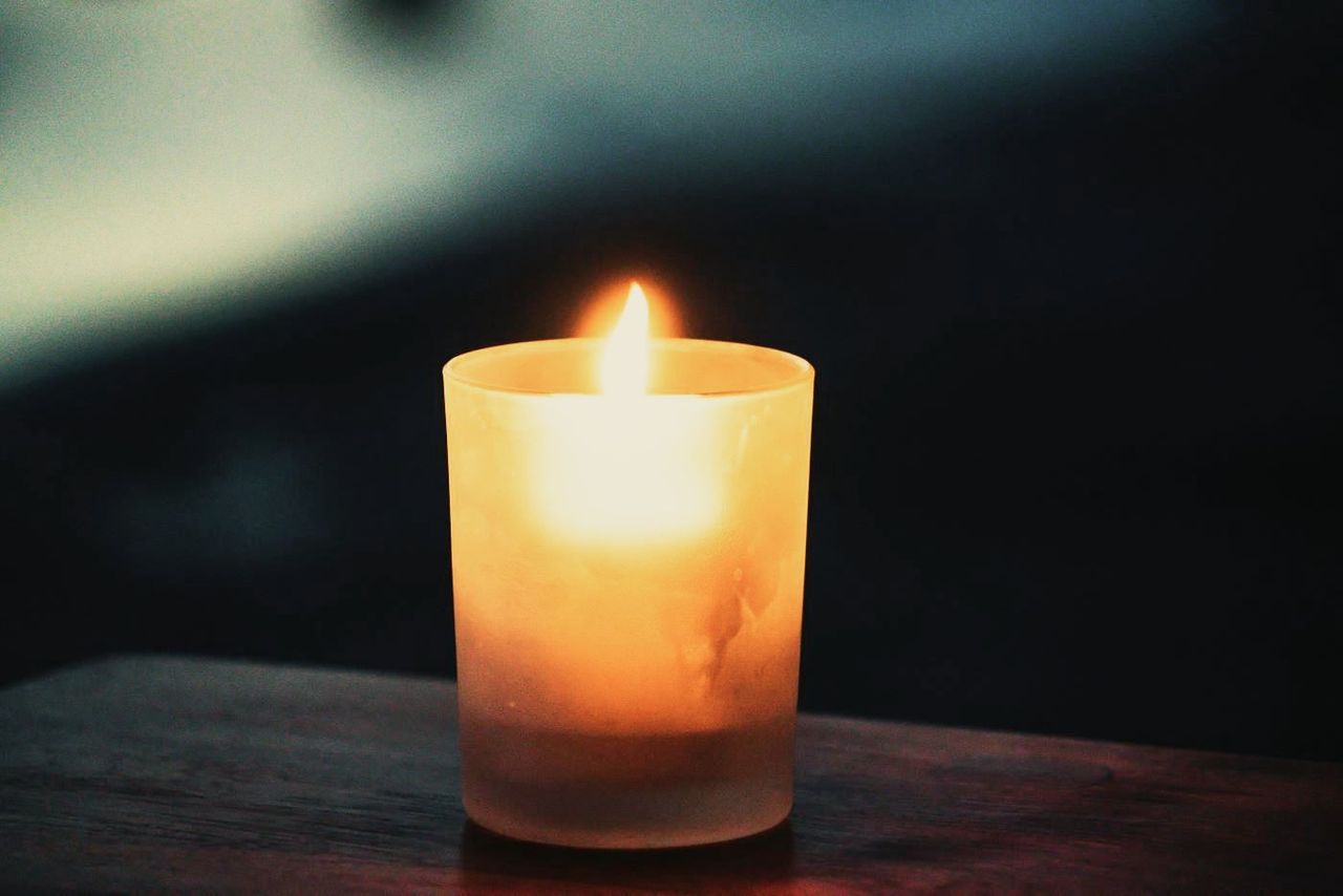 A lit candle in a glass on a table