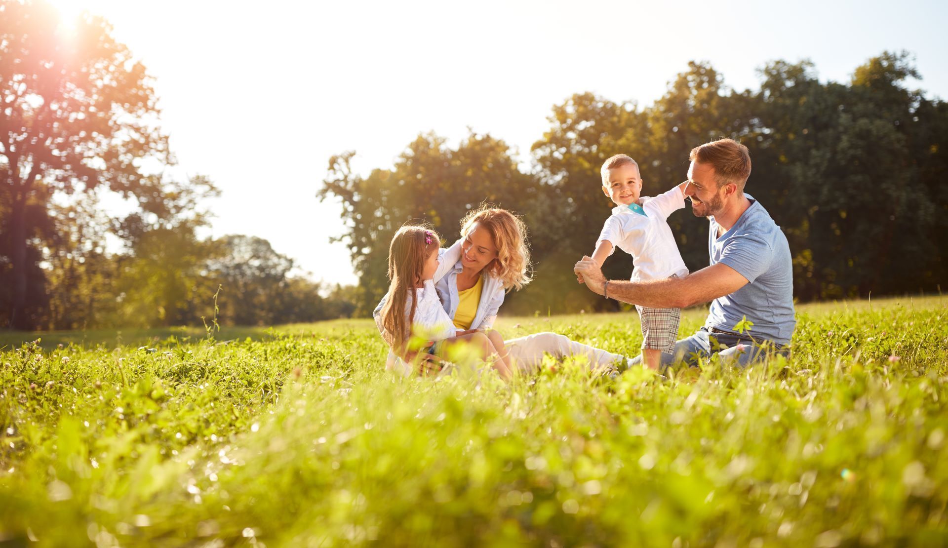 A family is sitting in the grass in a park.