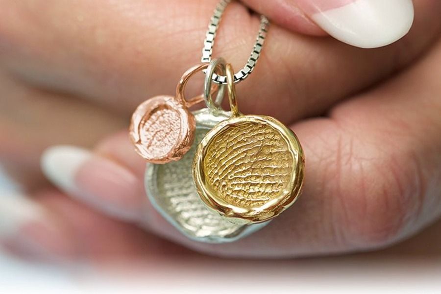 A hand holding fingerprint jewelry