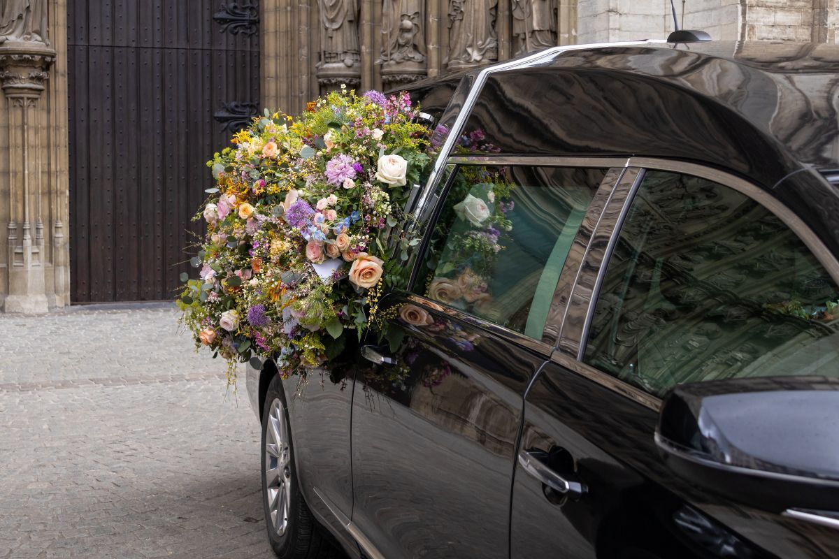 A black car with flowers on the side is parked in front of a building.