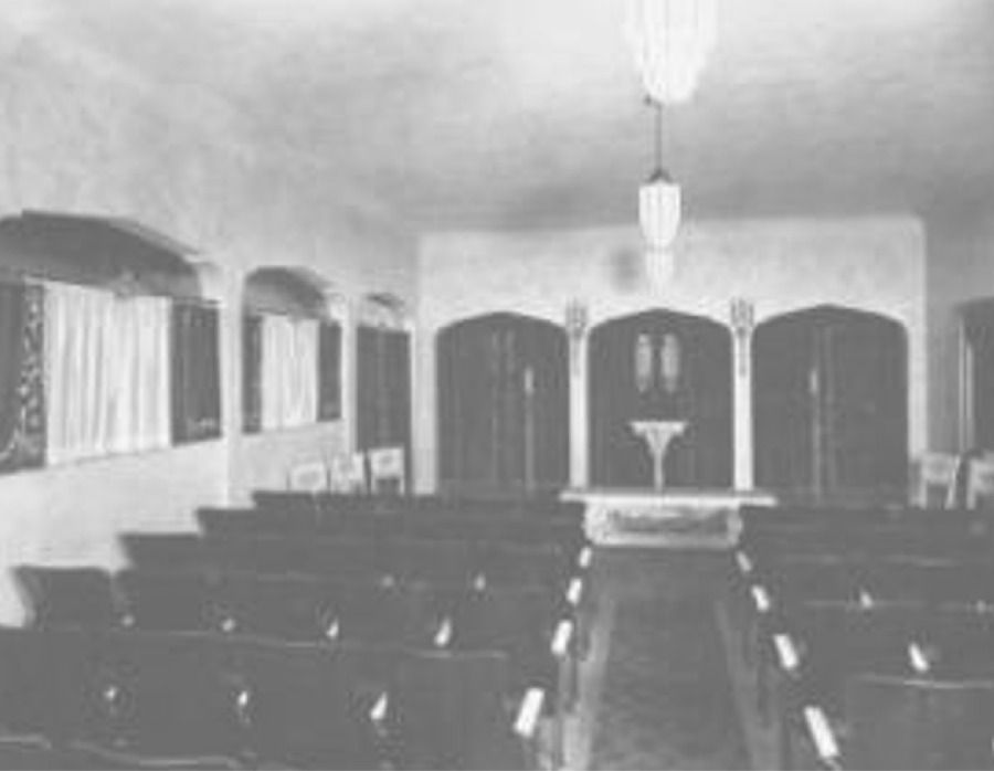 A black and white photo of a funeral chapel with rows of chairs and a podium.