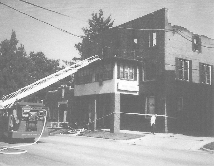 A black and white photo of a fire truck in front of a building