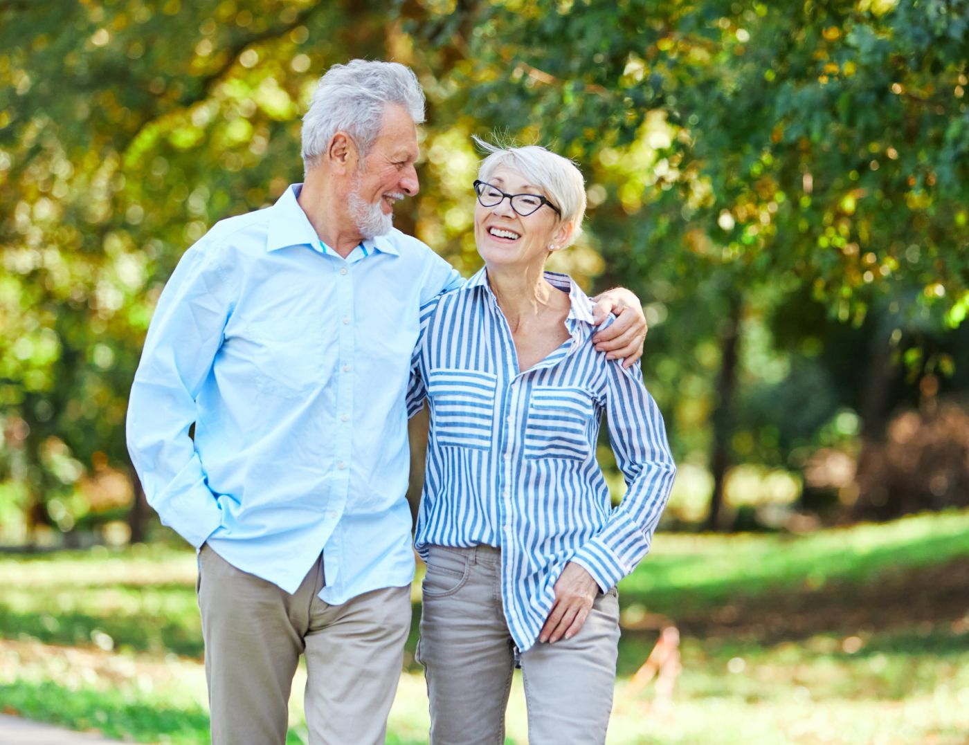 A man and a woman are walking in a park.