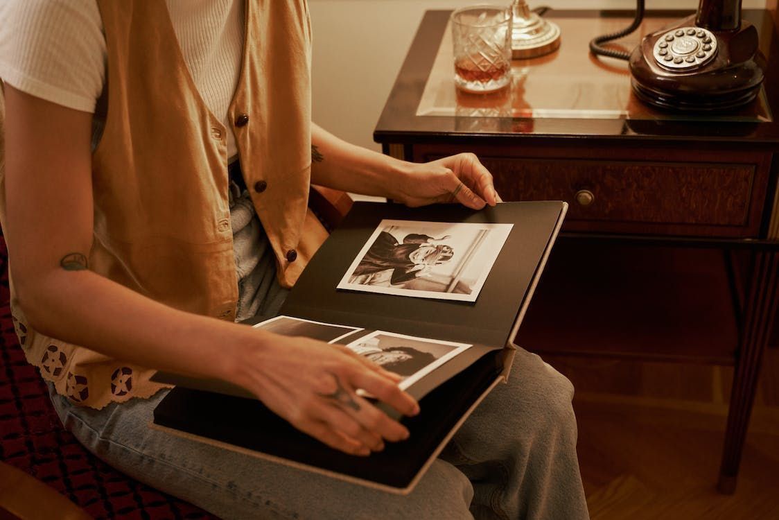 A man is sitting in a chair looking at a photo album.