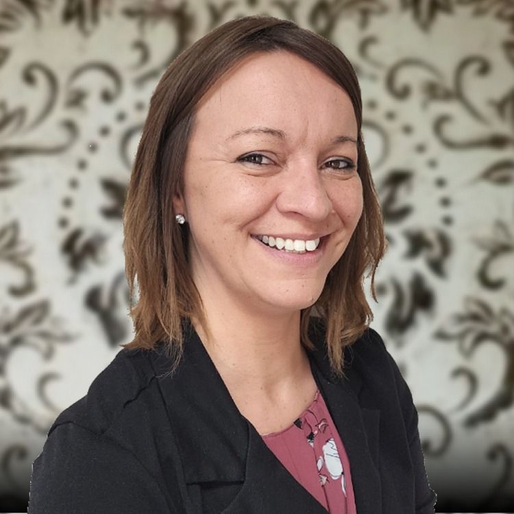 A road going through a field at sunset with the sun shining through the clouds.