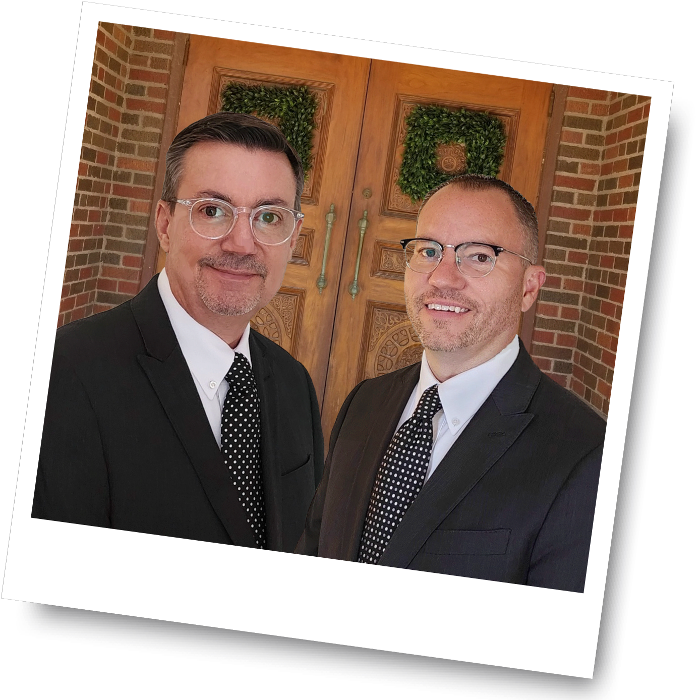Photograph of two men in front of brick building