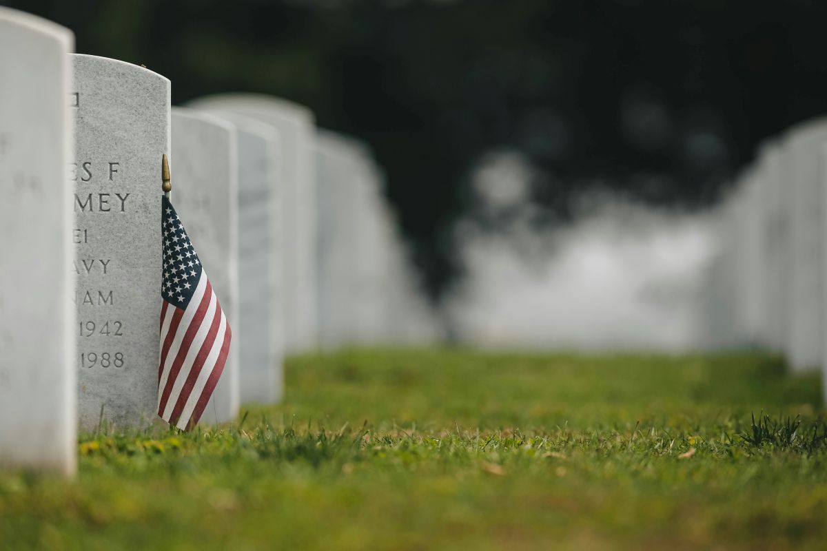 A grave with an american flag on it in a cemetery.