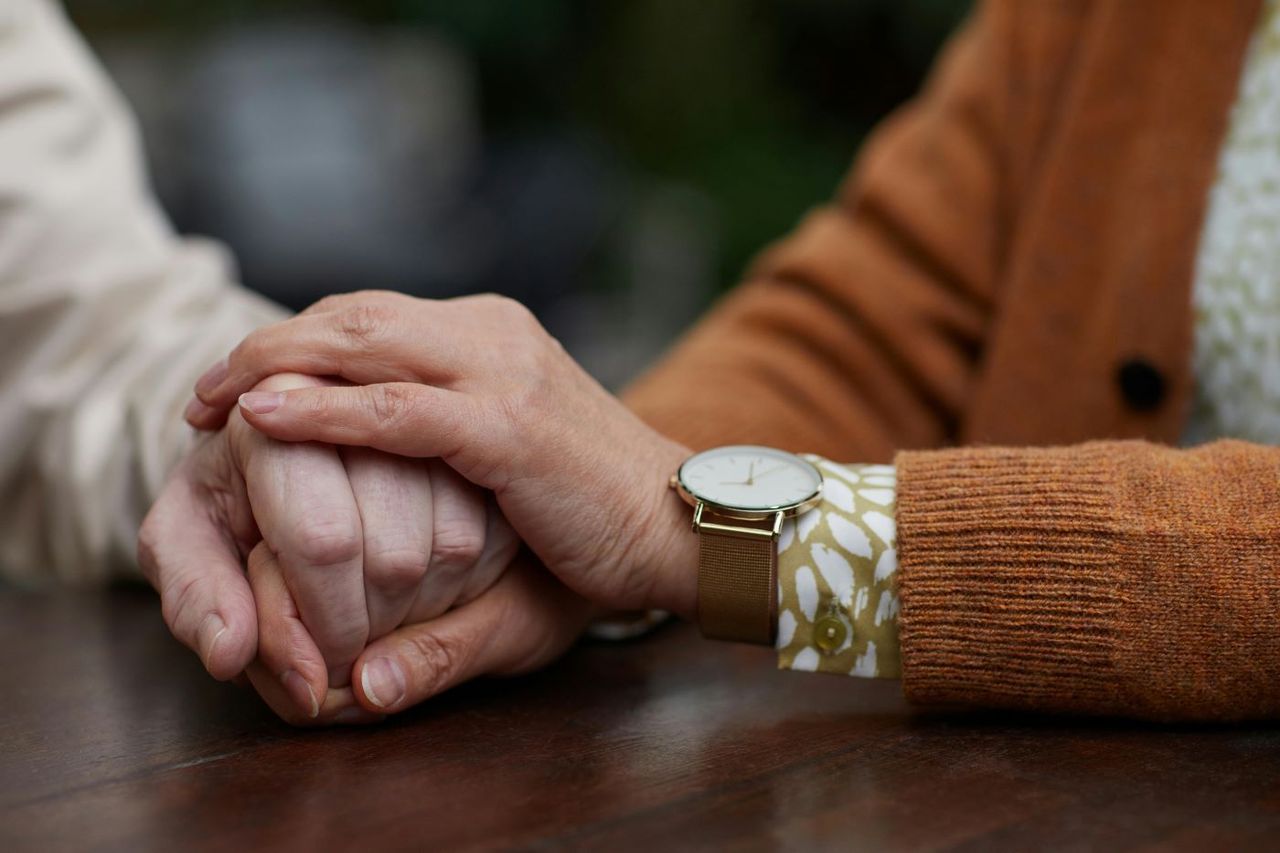 A woman is holding another woman 's hand while sitting at a table.