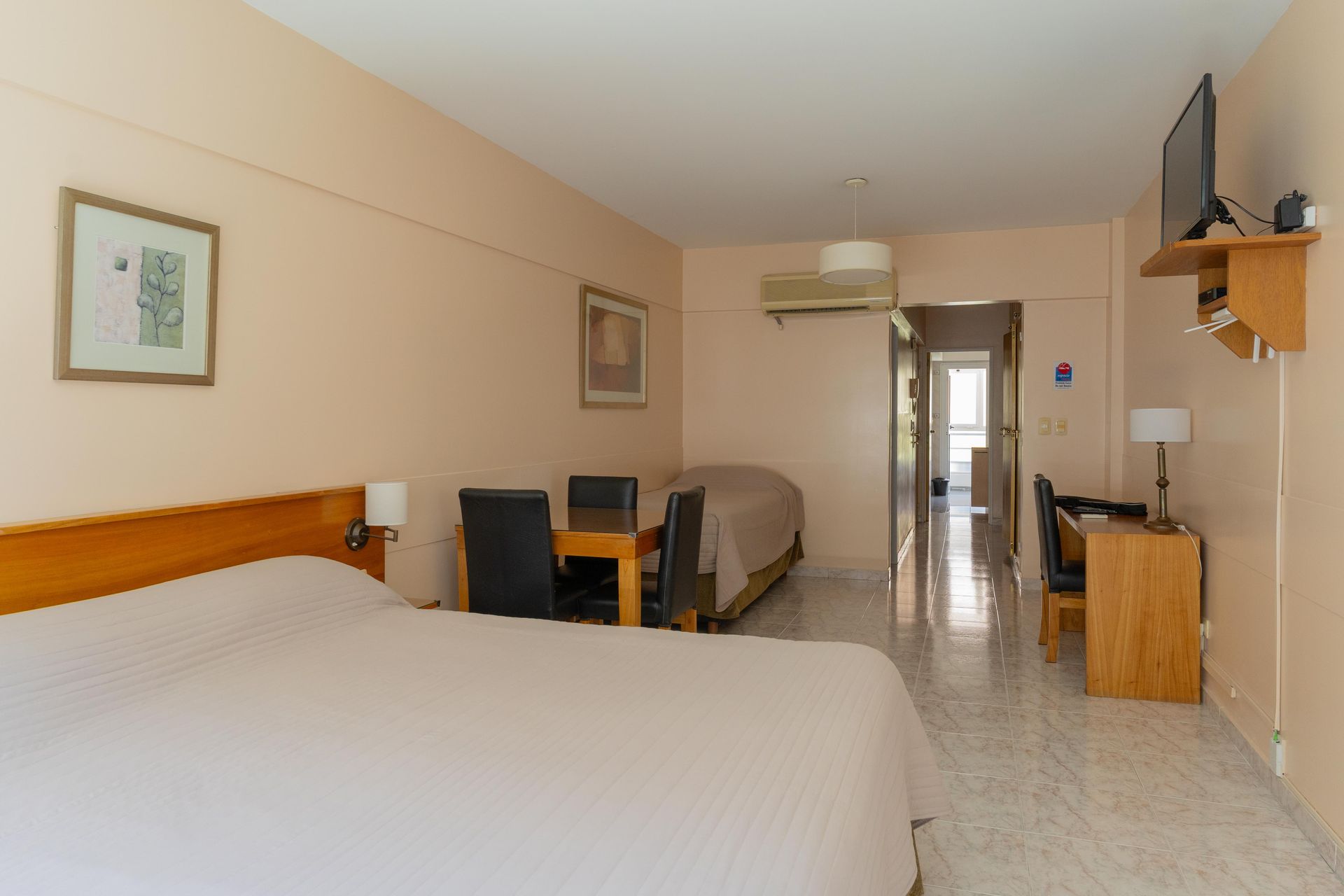 Una habitación de hotel con dos camas, una mesa y sillas.