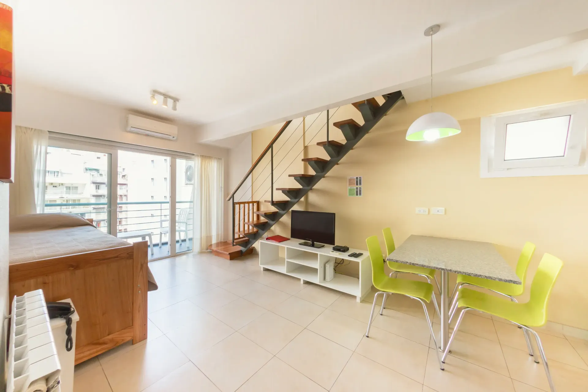Una sala de estar con una escalera y una mesa y sillas.