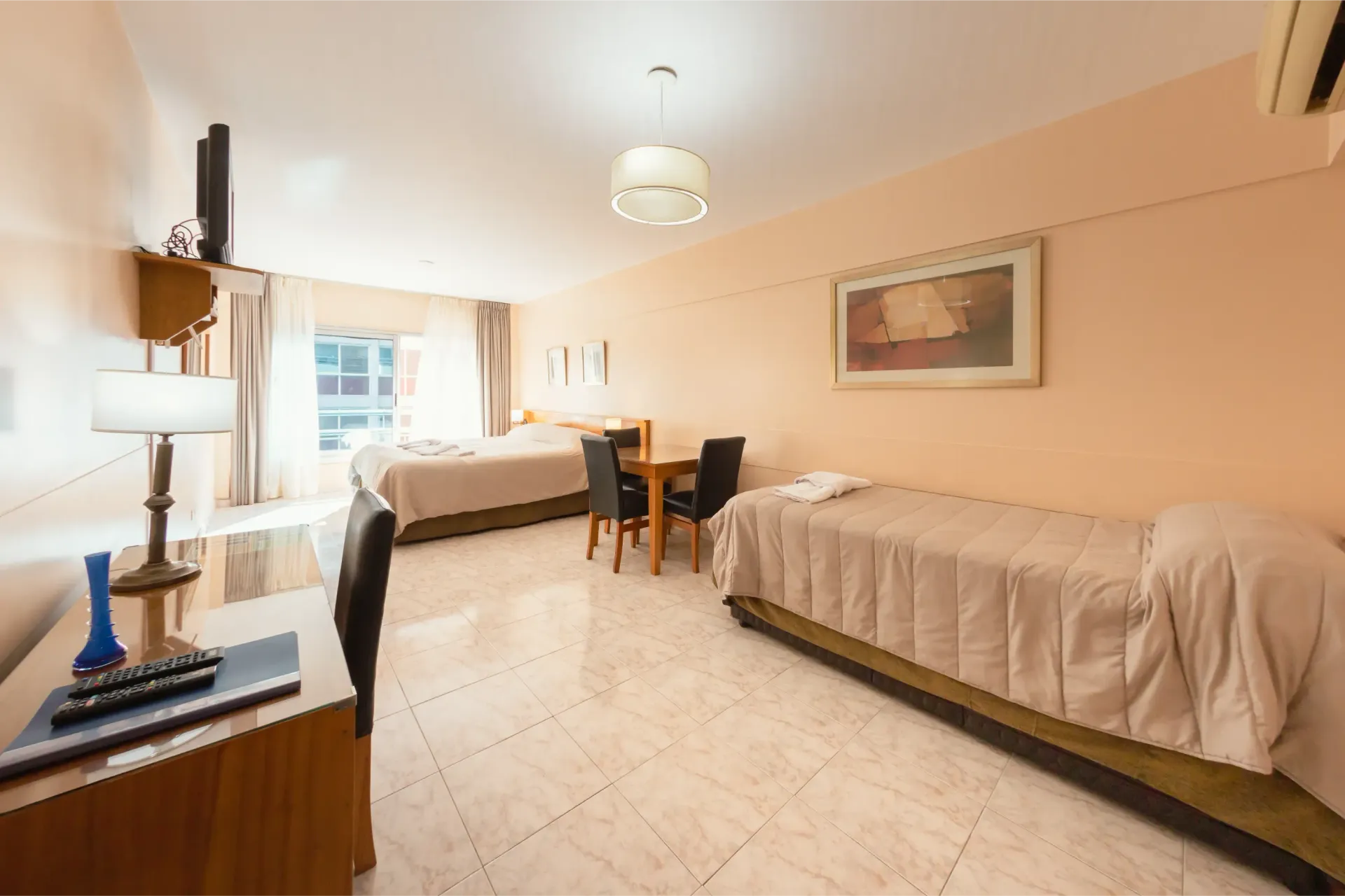 Una habitación de hotel con dos camas, una mesa y sillas.