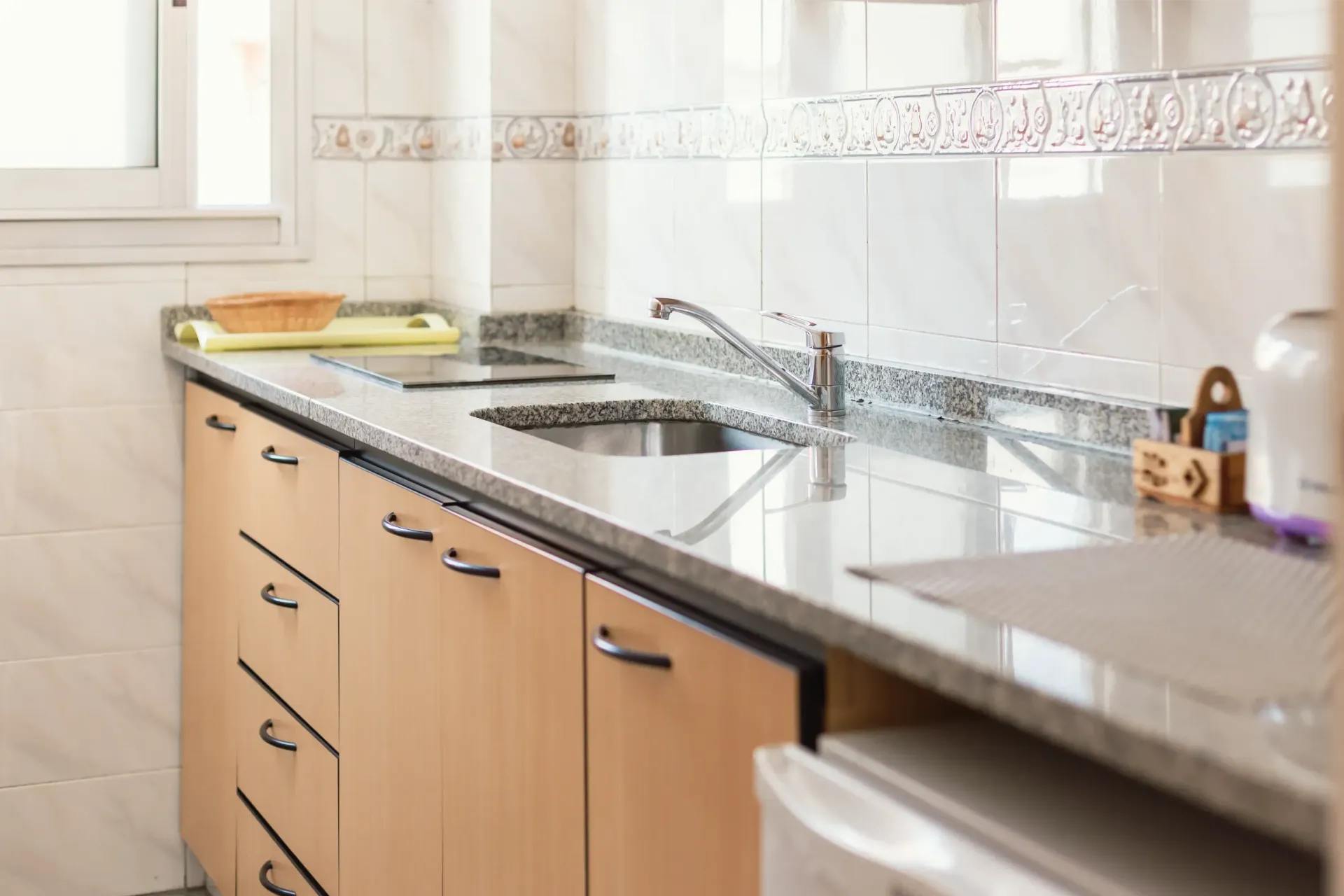 Una cocina con gabinetes de madera, encimeras de granito, un fregadero y una estufa.