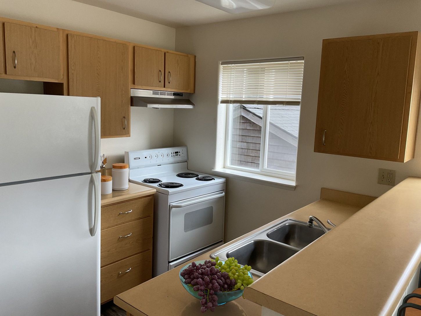 A kitchen with a stove , refrigerator , sink and window