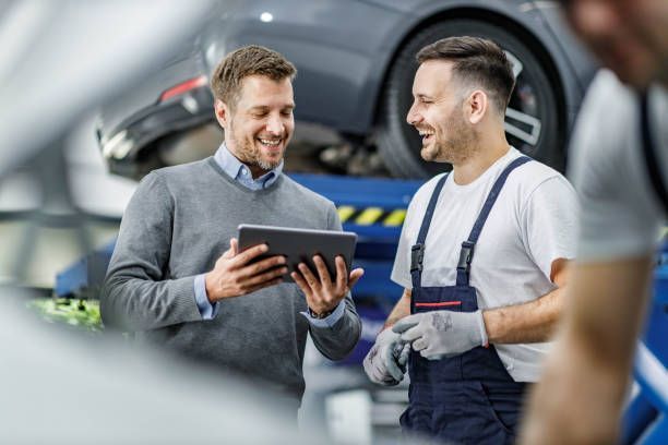 Two Men Are Looking at A Tablet in A Garage.