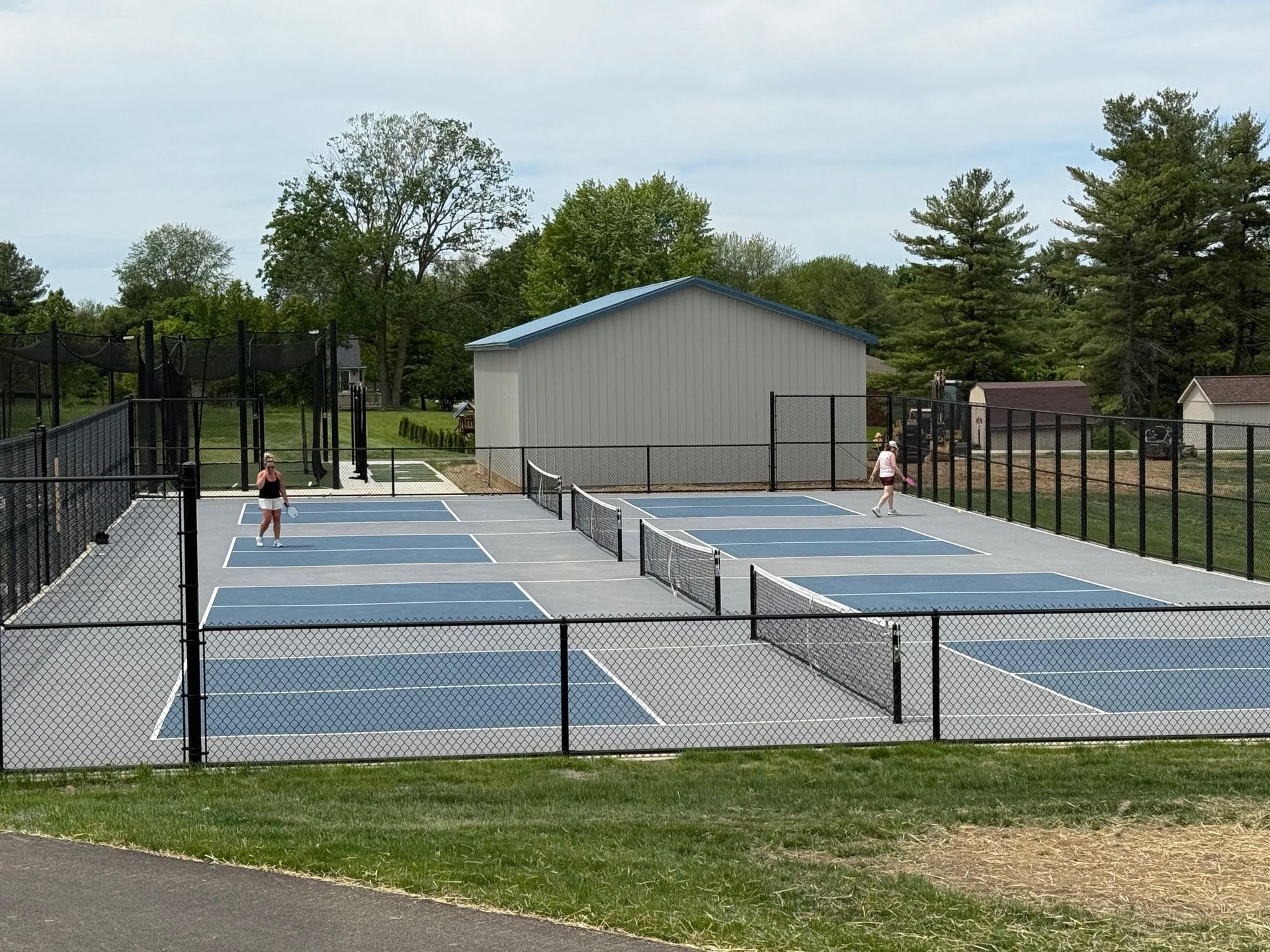 Green and red rooftop sports court with volleyball and basketball lines, overlooking cityscape.