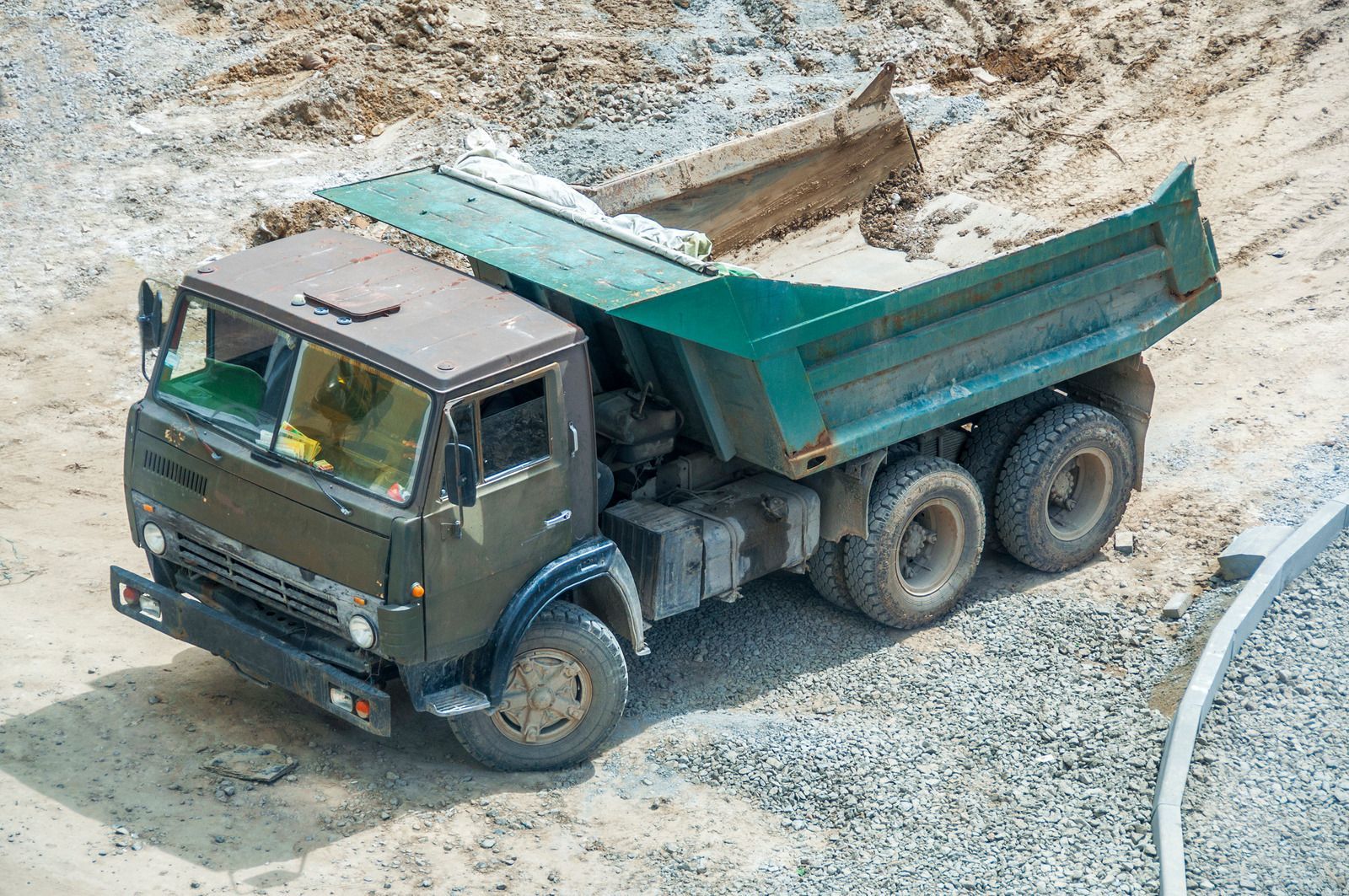 A dump truck is driving down a dirt road.