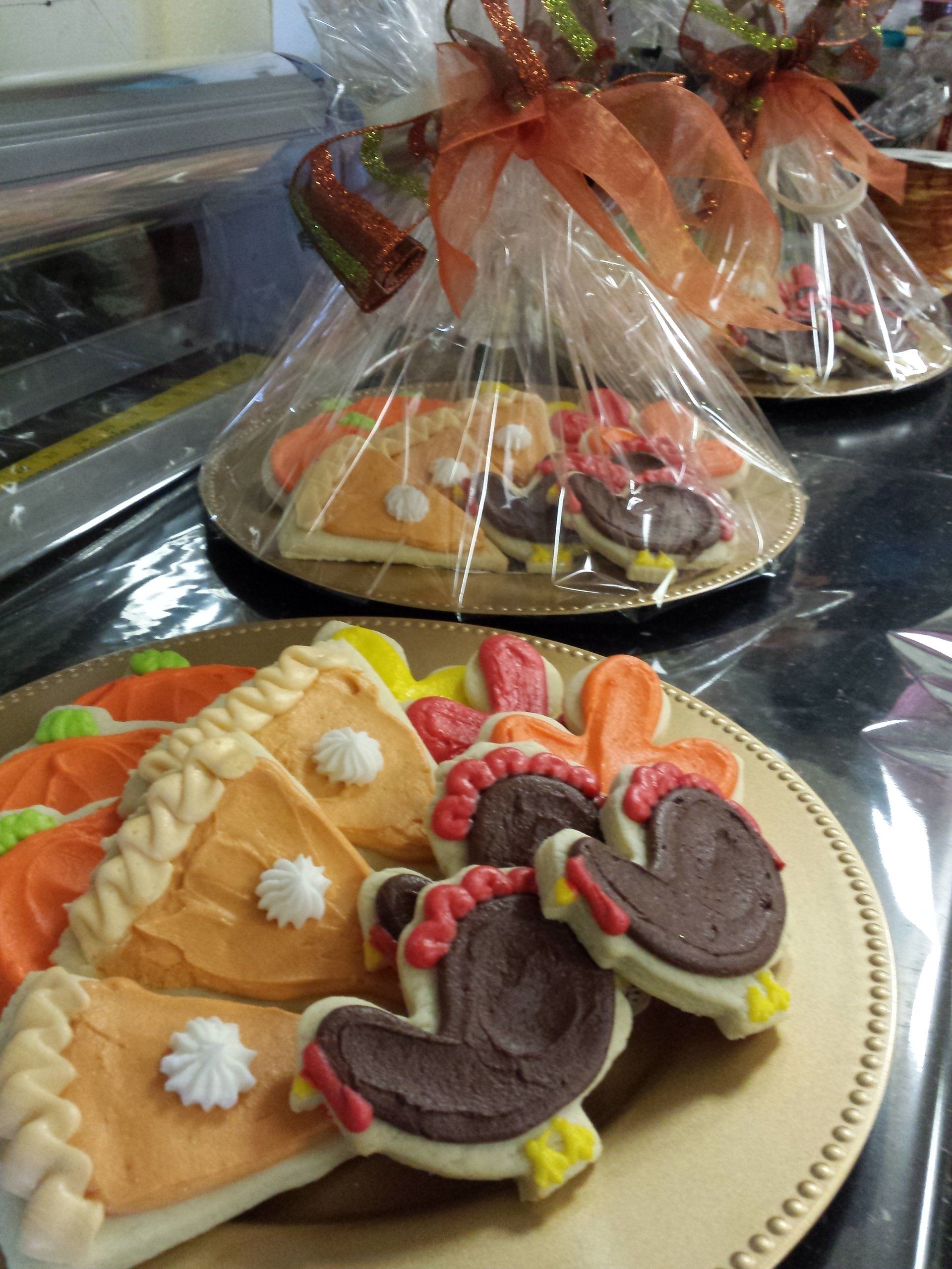 A tray of sugar cookies shaped and iced like Thanksgiving turkeys, pie, pumpkins and leaves