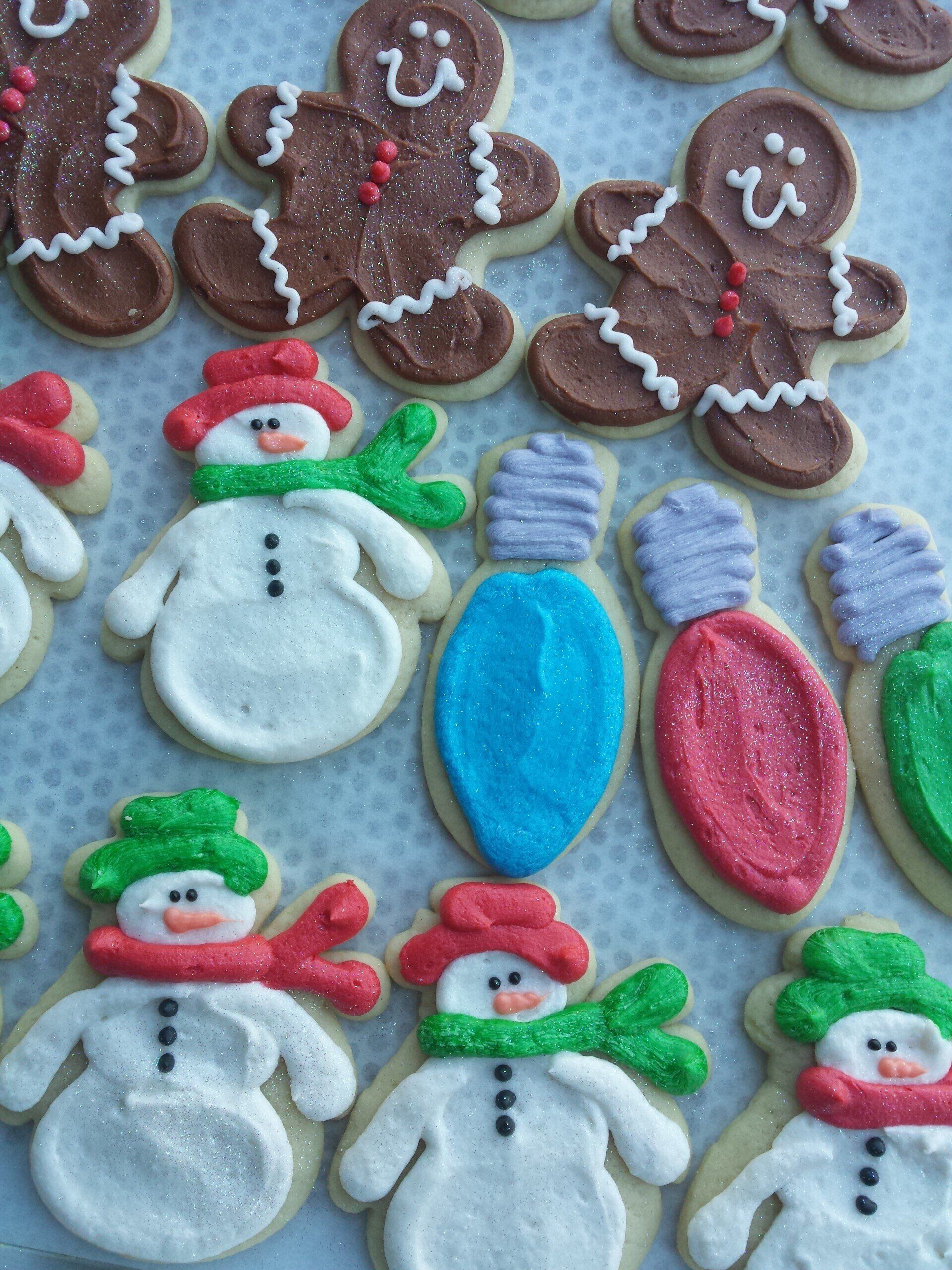 A tray of sugar cookies shaped and iced like snowmen, lights, and gingerbread men