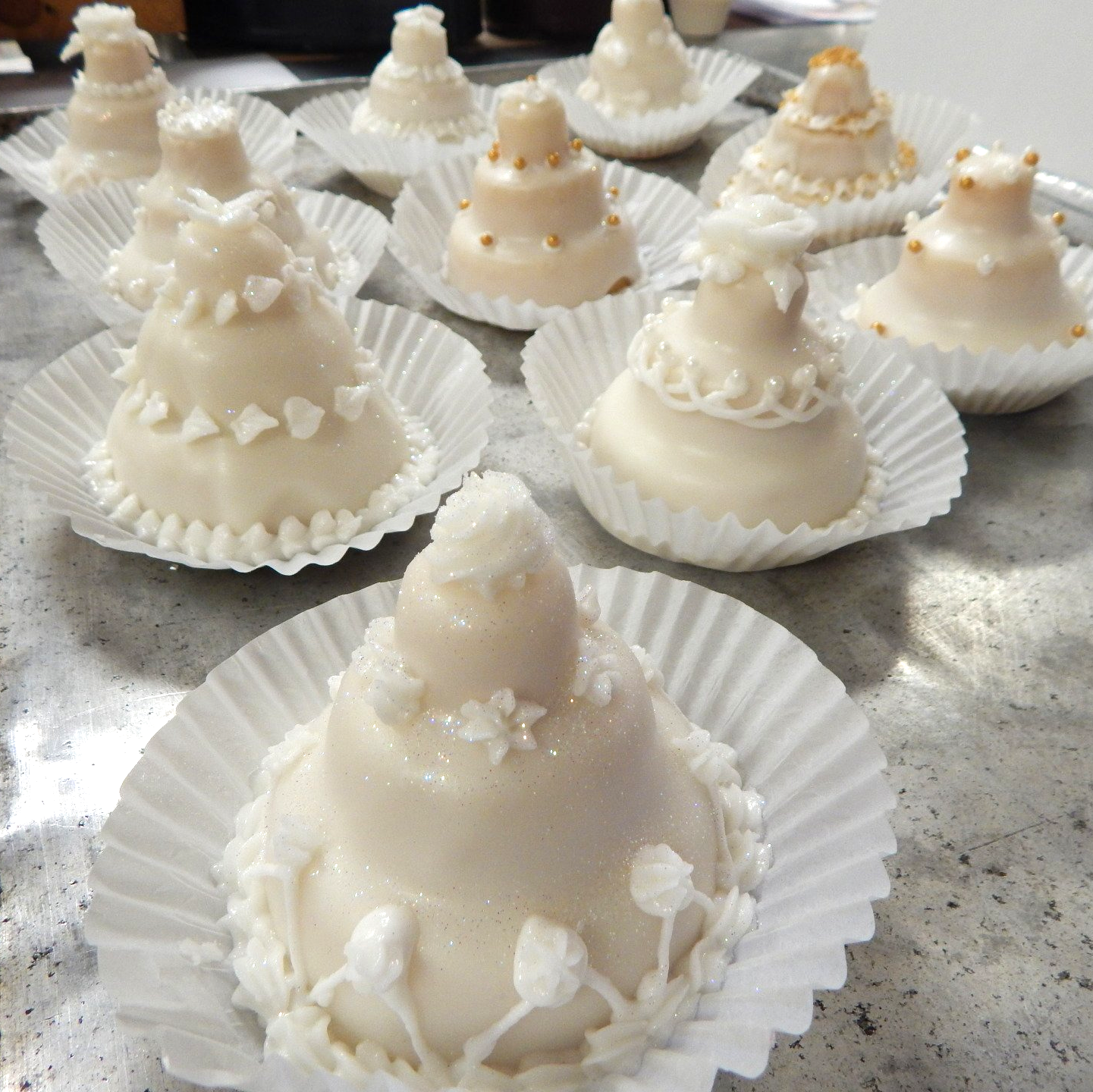 Cake balls in white chocolate shaped like little tiered wedding cakes