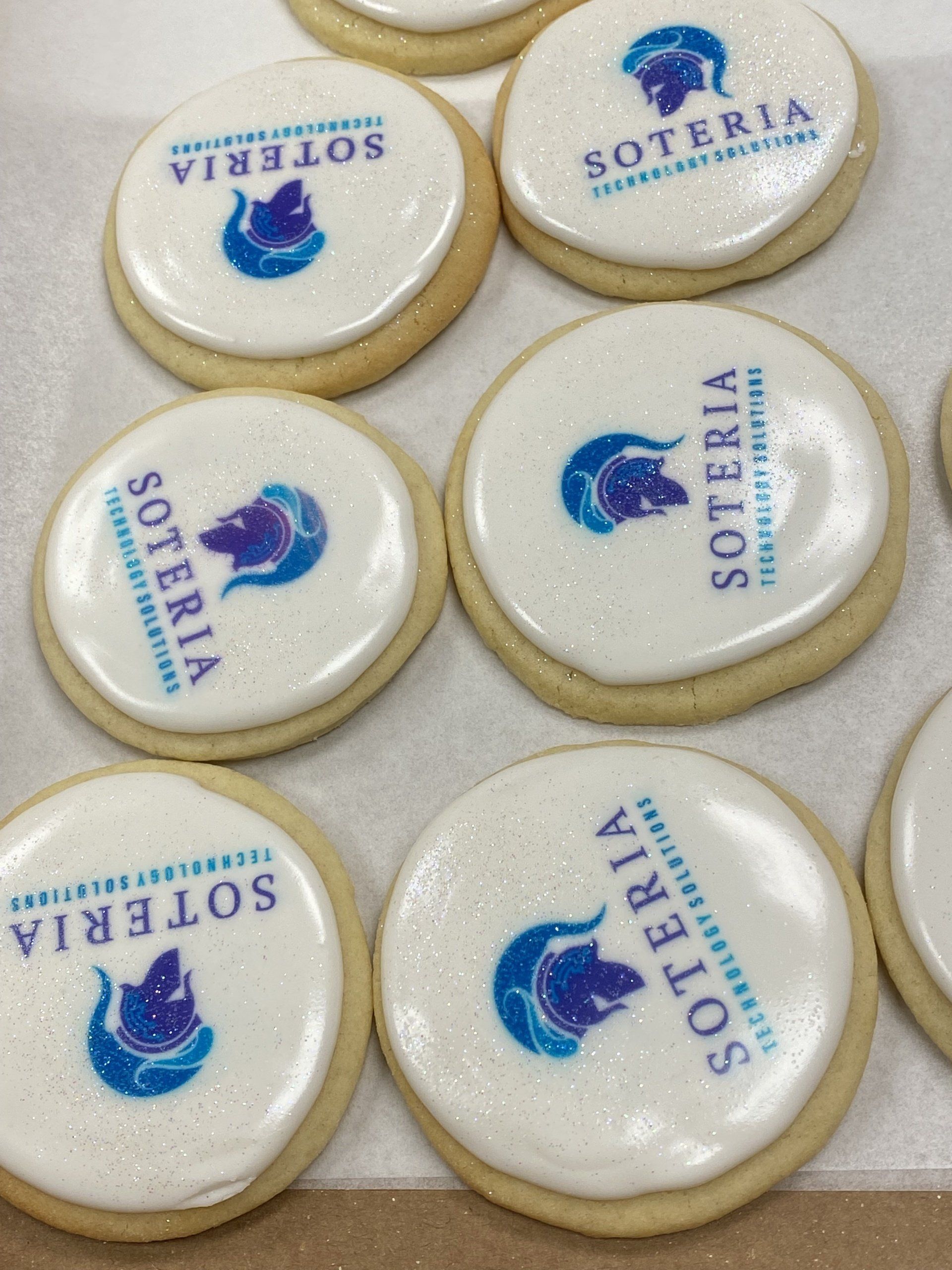 A tray of sugar cookies with royal icing and logos printed on top