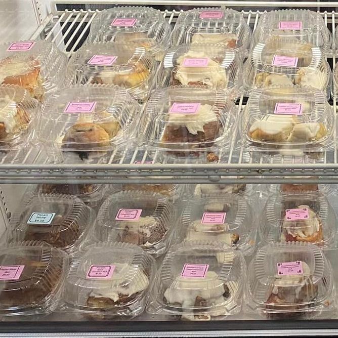 A display case full of individually wrapped cinnamon rolls in a variety of flavors