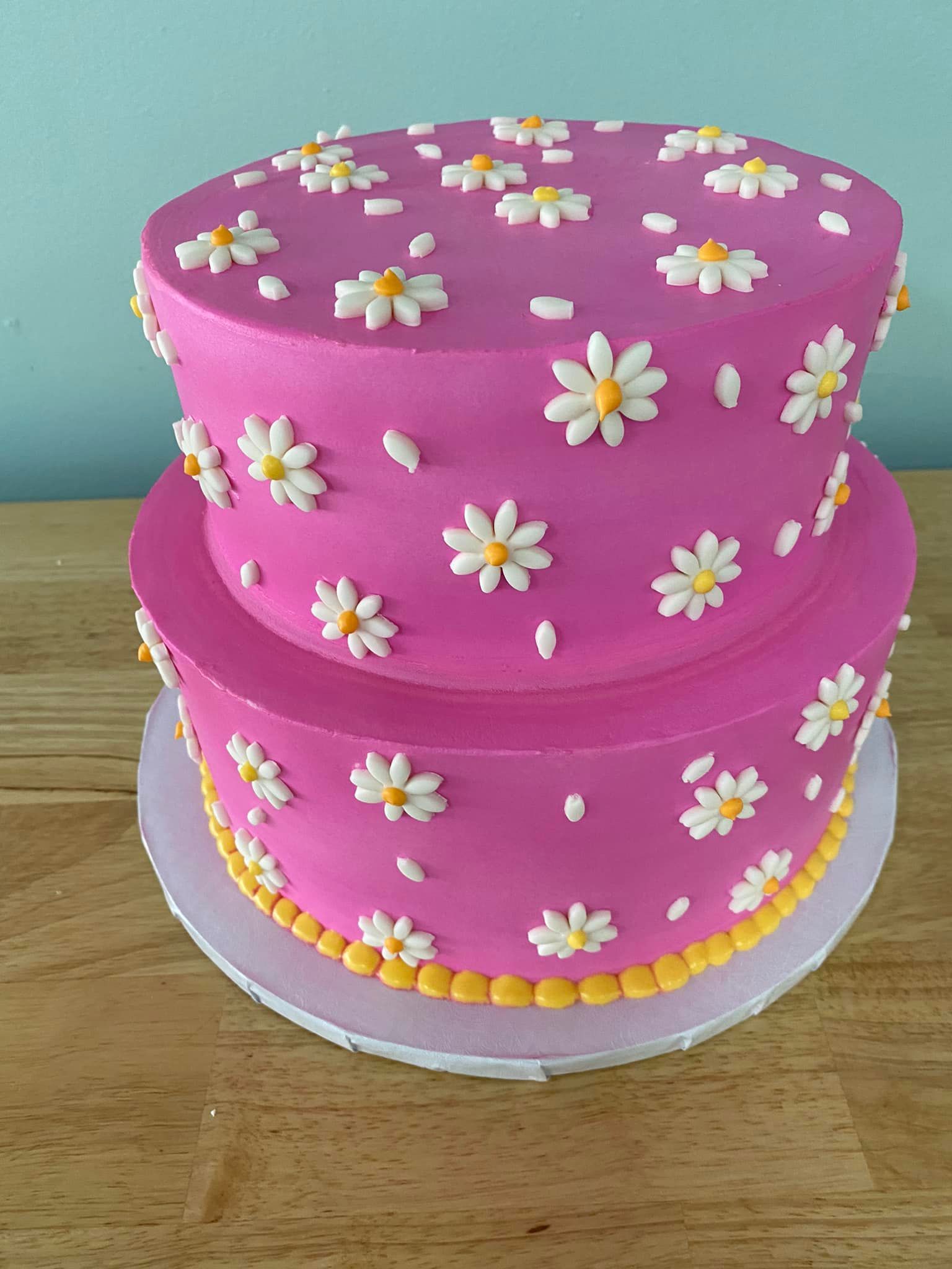 pink cake with white iced daisies