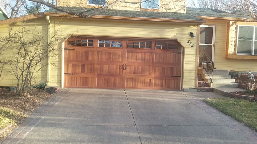 Garage with brown door and yellow siding on a house with a concrete driveway.