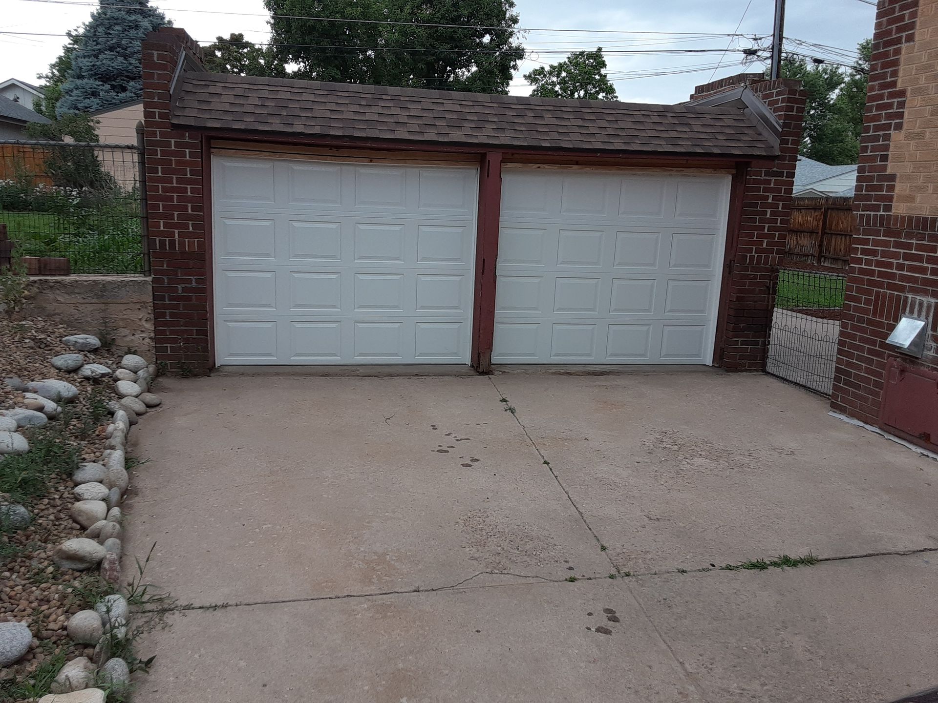 Two-car garage with white doors and brick exterior; concrete driveway.