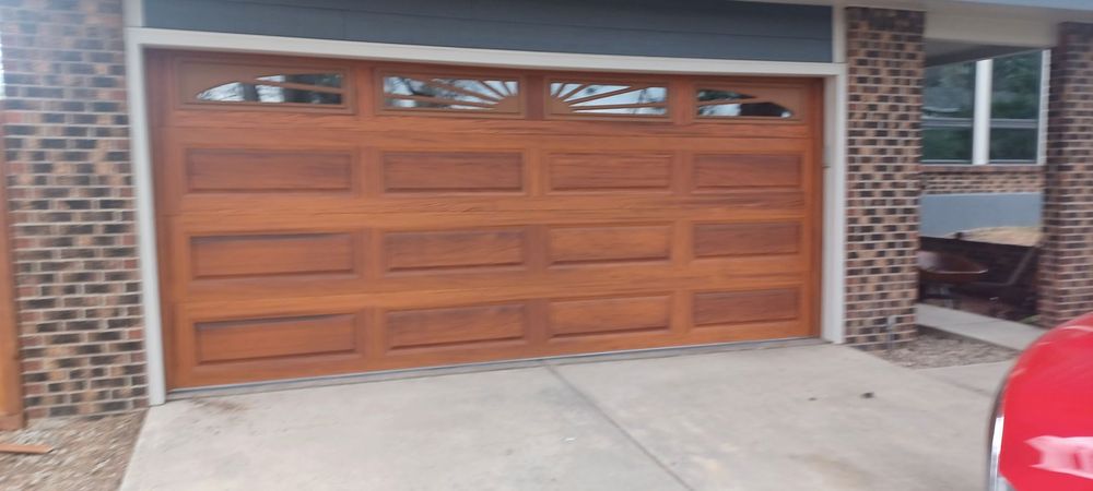 Brown garage door on a concrete driveway, with a red car visible.