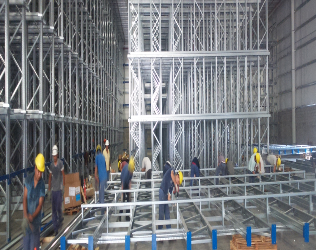 Obreros montan estanterías metálicas dentro de un almacén. 