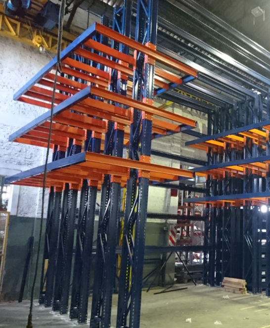 Sistema de estanterías para almacén industrial; construcción en acero naranja y azul.