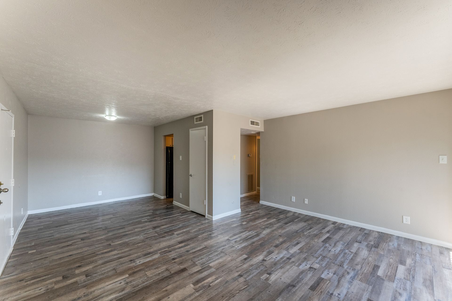 An empty living room with hardwood floors and a ceiling fan.