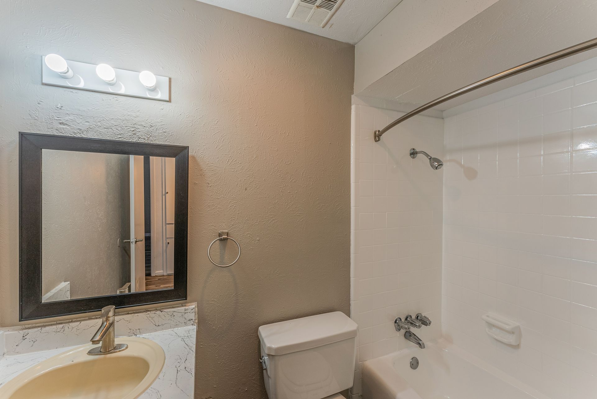 A bathroom with a sink , toilet , shower and mirror.