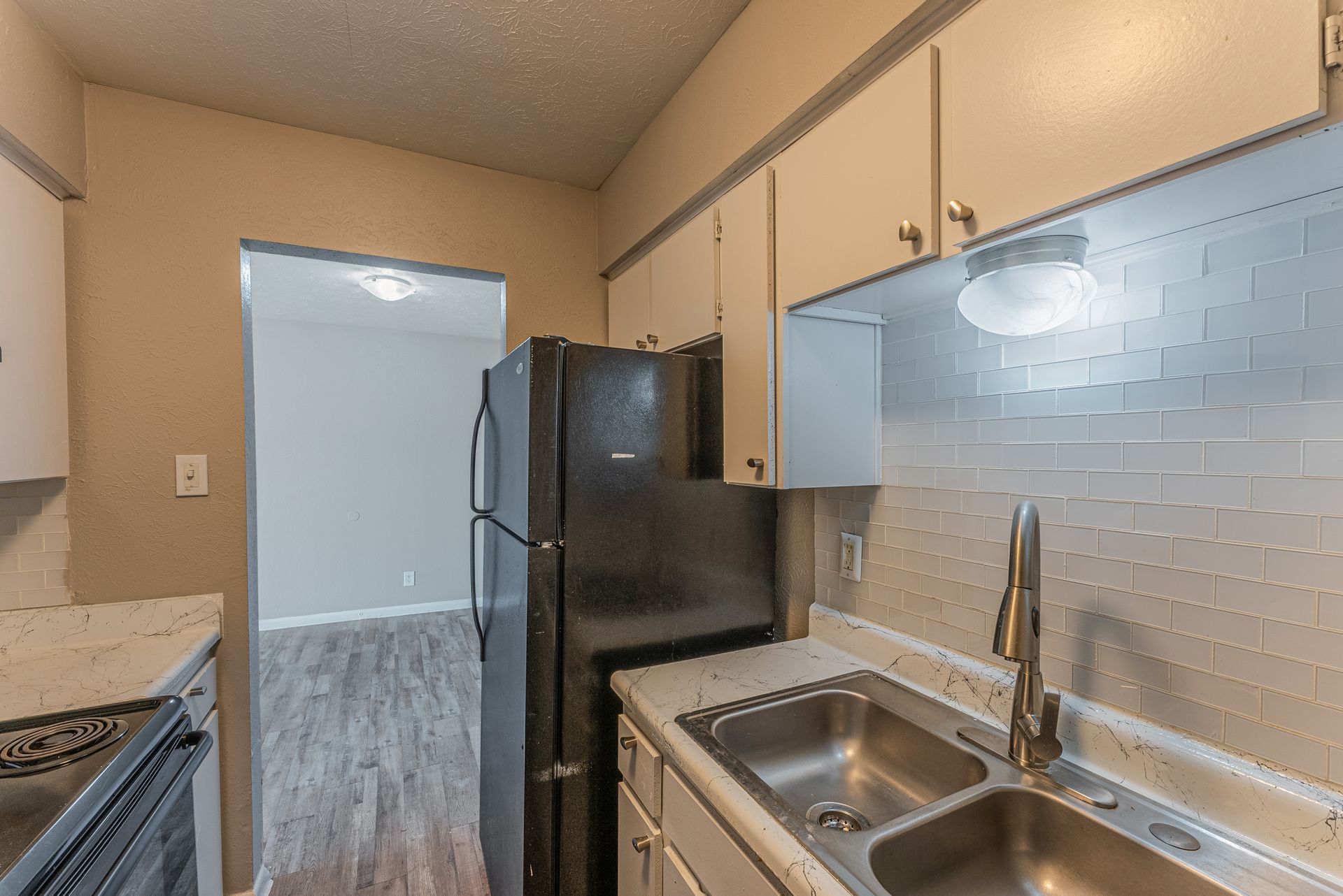 A kitchen with a sink , refrigerator , and microwave.