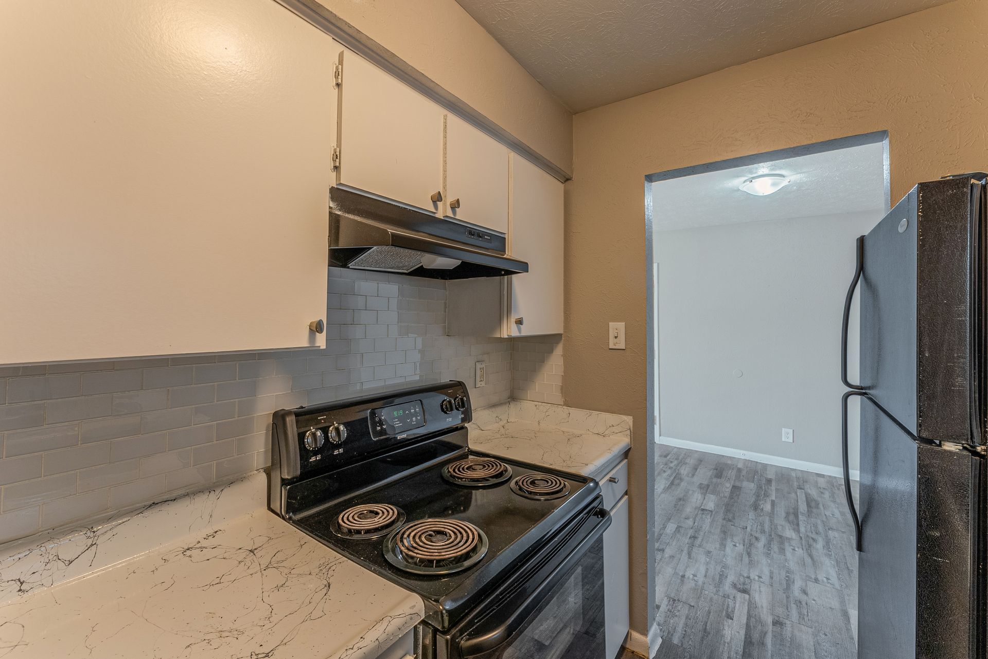 A kitchen with a stove , refrigerator , and cabinets.