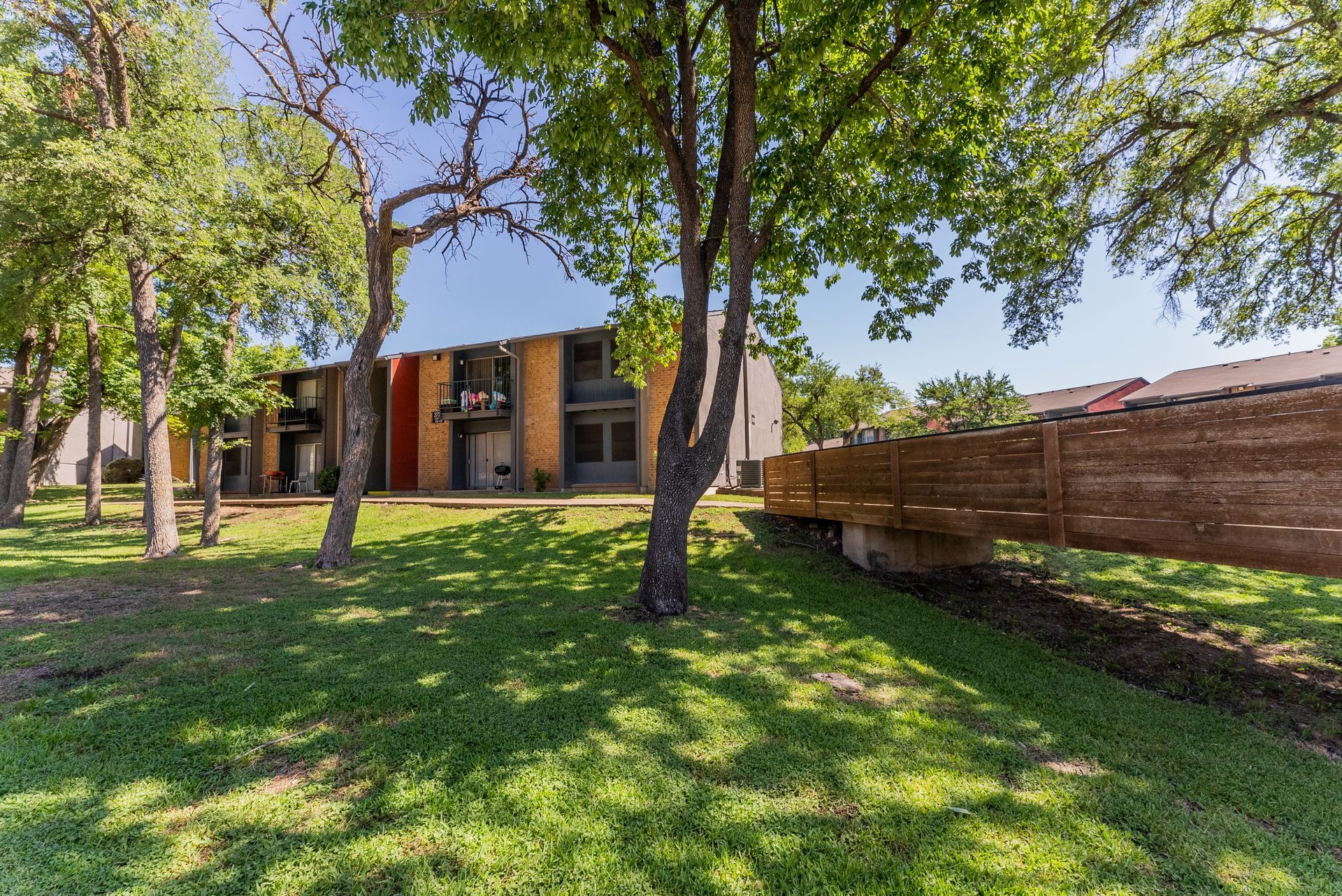 A house with a wooden fence and trees in front of it.
