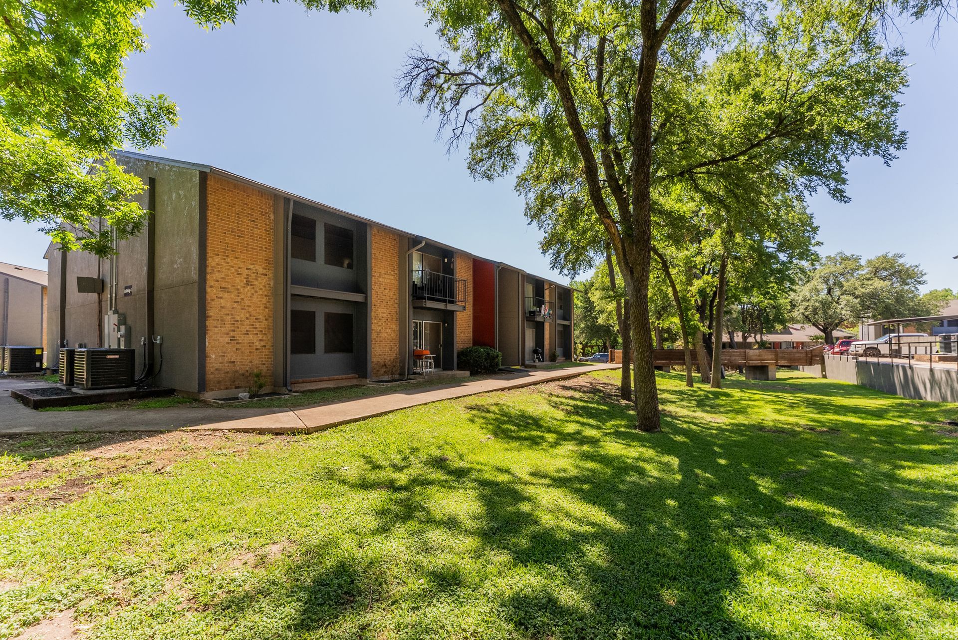 A large apartment building with a lot of grass and trees in front of it.