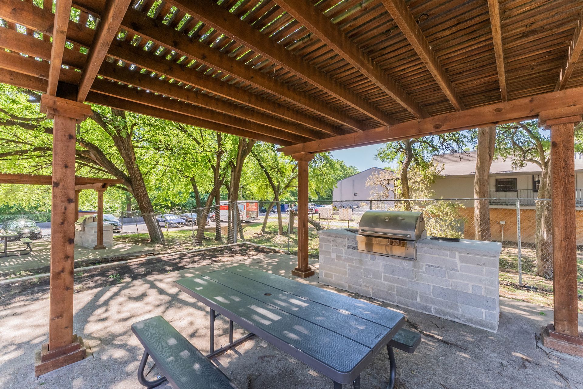 A picnic table and benches under a wooden pergola.