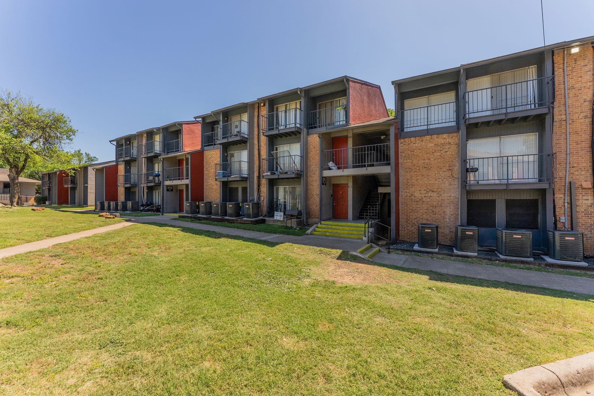 A row of apartment buildings with a lush green lawn in front of them.