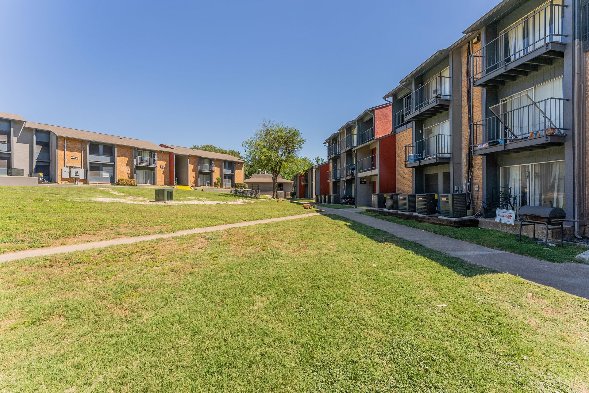 A row of apartment buildings with a large lawn in front of them.