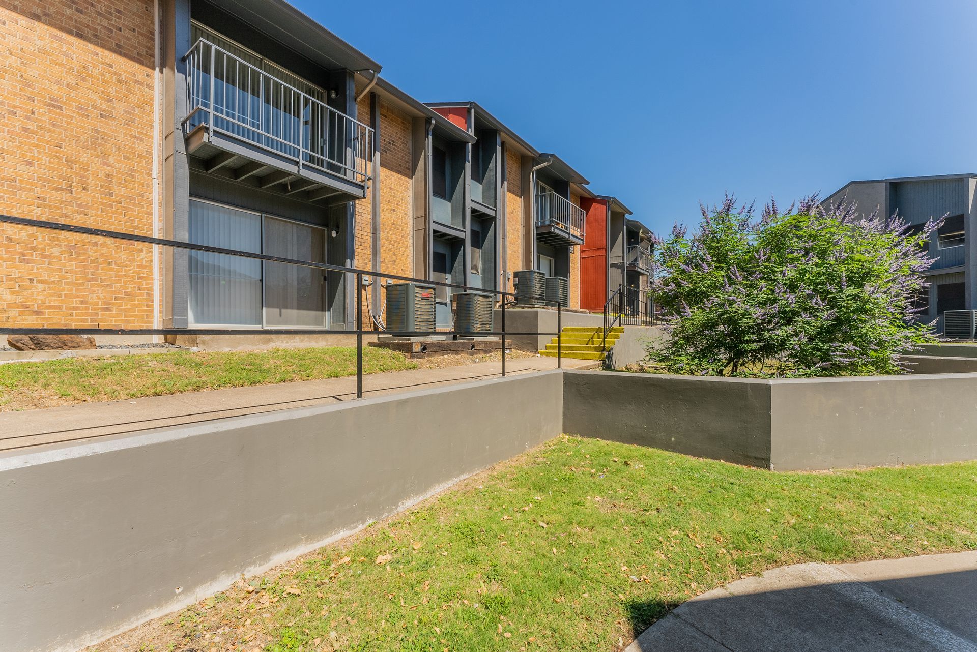 A row of apartment buildings with a walkway leading to them.
