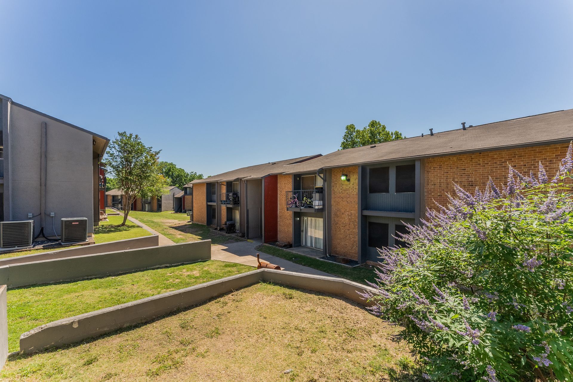 A row of apartment buildings with a lush green lawn in front of them.
