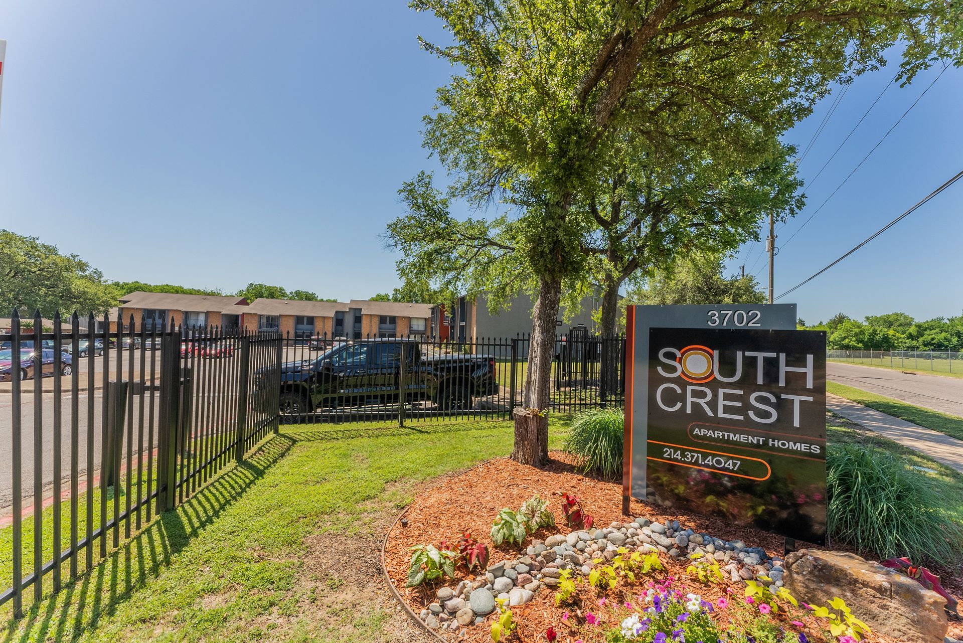 A sign for south crest apartments is in front of a fence.