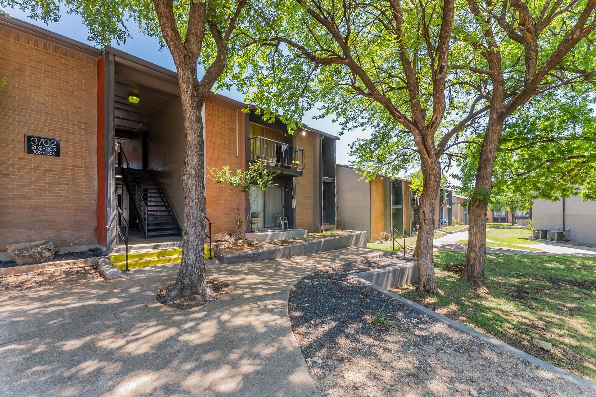 A brick apartment building with trees in front of it.