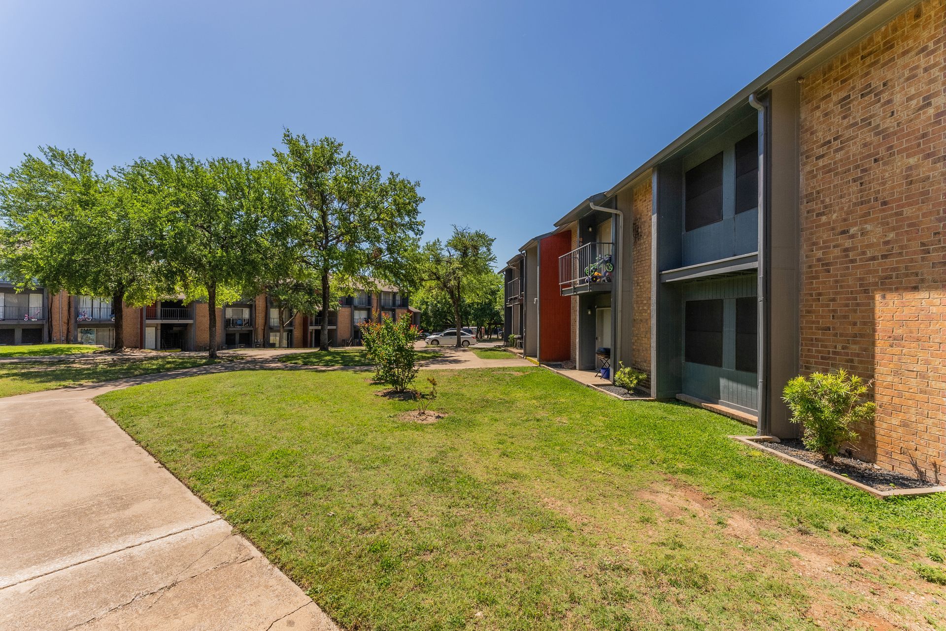 A row of apartment buildings with a lush green lawn in front of them.