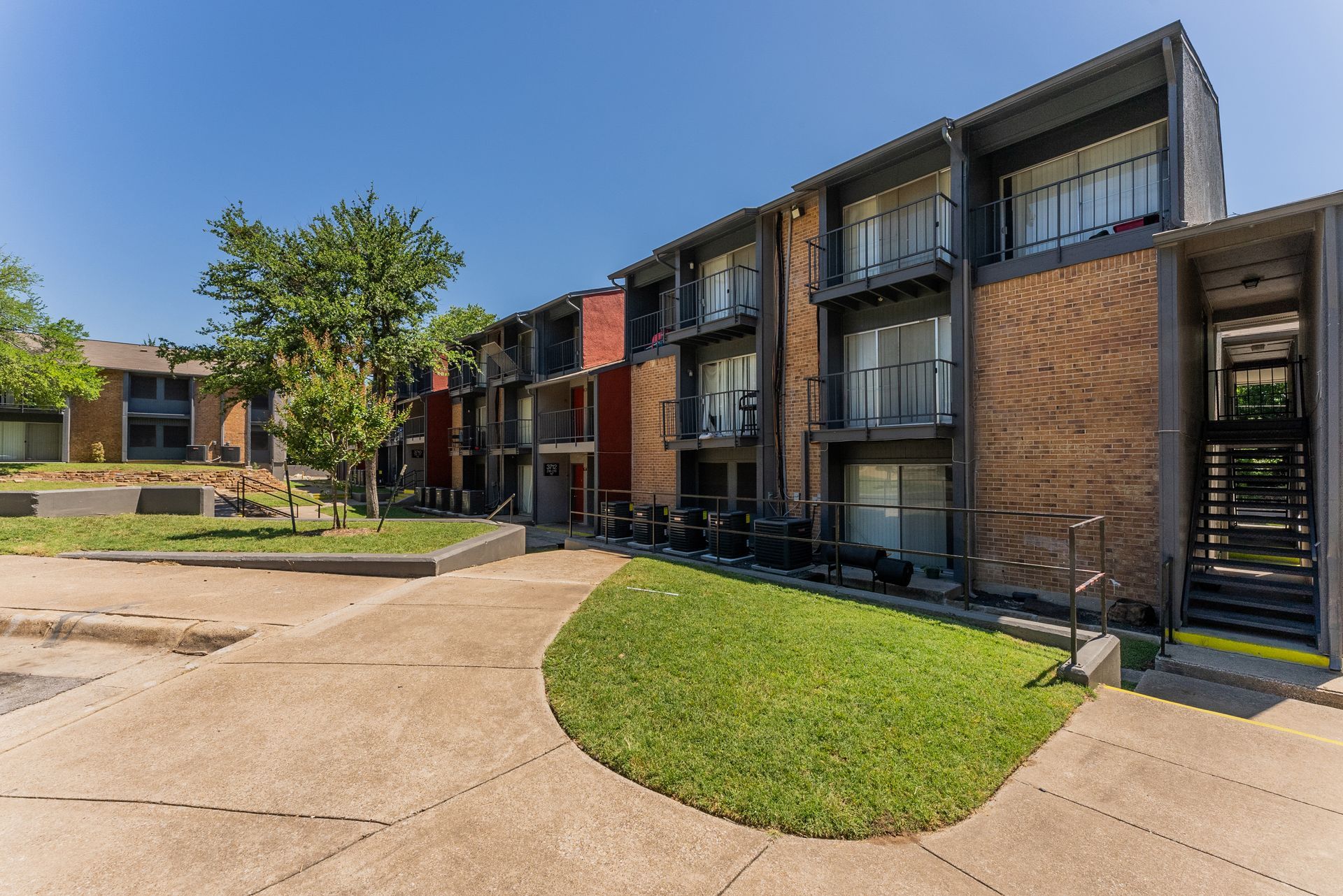 A large apartment building with a lush green lawn in front of it.